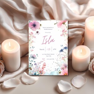 Floral watercolor bridal shower invitation displayed among lit candles and rose petals for a romantic, elegant styling.
