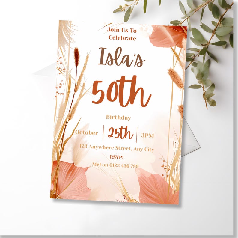 Angled close-up of the boho birthday invitation styled with green leaves on a light backdrop