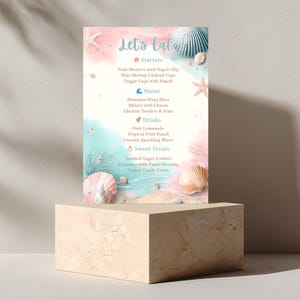 May include: A menu with the text "Let's Eat" in a whimsical font, featuring starters, mains, drinks, and sweet treats. The design incorporates a beach theme with seashells, starfish, and pastel colors of pink and teal. The menu is displayed on a beige pedestal.