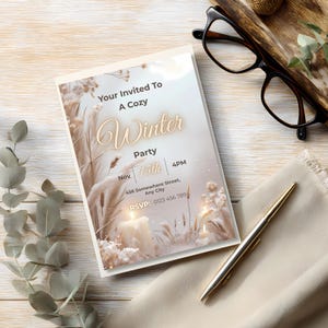 Neutral boho winter invitation styled on a wood desk with glasses, pen, and eucalyptus leaves