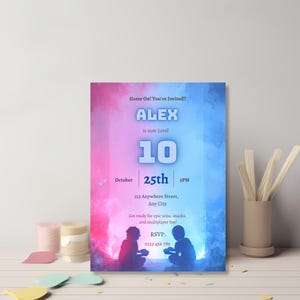 Neon gamer birthday invitation card styled on a shelf with party decor, Level Up video game theme invite for boys birthday