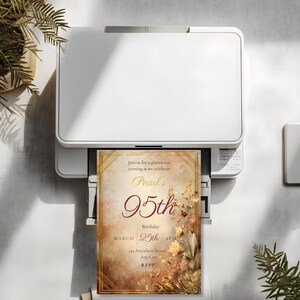 95th birthday invitation template printing from a white home printer, showing the full Art Deco amber floral design emerging from the printer tray