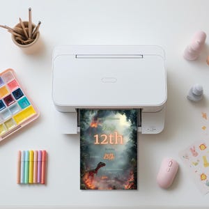 May include: A white printer is printing a birthday invitation with a dinosaur theme. The invitation reads "Ben's 12th Birthday" with the date October 25th. Other items on the white surface include art supplies and a pink mouse.