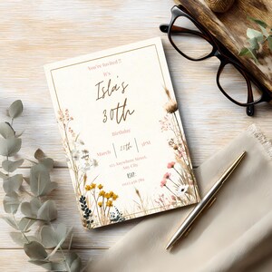 May include: An invitation card with a floral design and the text "Isla's 30th Birthday." The card includes the date, time, and RSVP information. The design features a cream background with gold accents and floral illustrations.