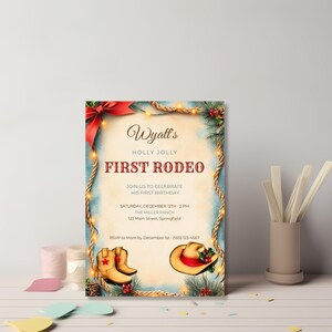 Printable cowboy Christmas birthday invitation standing on a shelf, featuring rope lasso border, string lights, pine, holly and pinecones