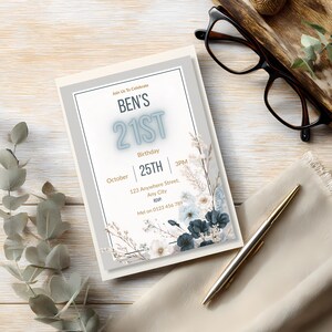 May include: A cream-colored invitation with the text "BEN'S 21ST" in blue. The invitation includes details for a birthday celebration on October 25th at 3 PM. Floral accents in white and blue decorate the edges. A pen and glasses are also visible.