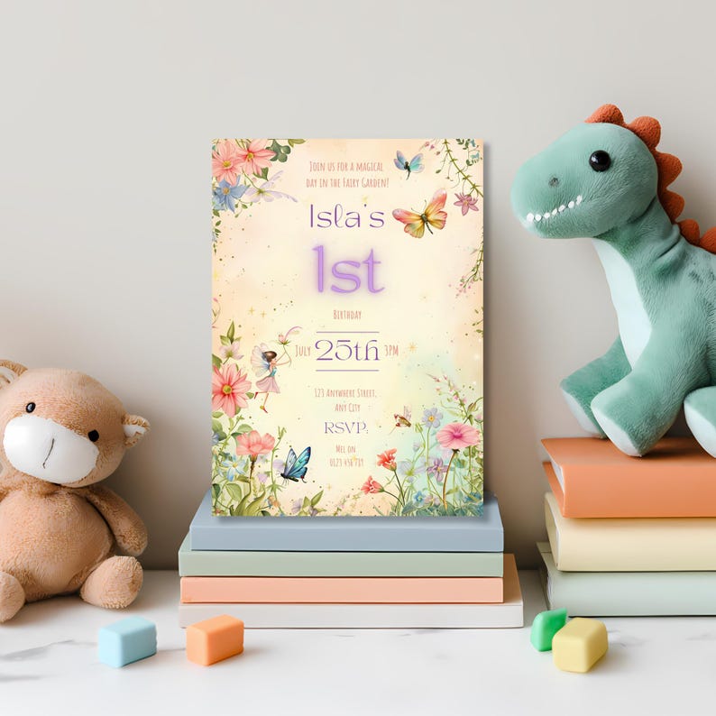 Editable fairy garden birthday invitation standing on a stack of pastel books between a teddy bear and dinosaur plush toy, showing the enchanted garden design with fairy, butterflies and botanical florals