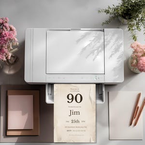 Printed 90th birthday invitation coming out of printer, vintage newspaper style design, high resolution printable invite