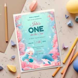 Under the sea first birthday invitation flat-lay with colored pencils and paper shapes, featuring a chibi mermaid and dolphin.