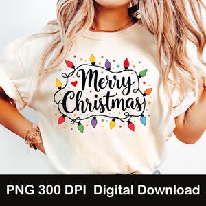 May include: A white t-shirt with the text "Merry Christmas" in black script surrounded by a string of colorful Christmas lights.