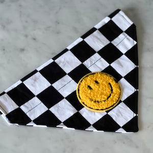 May include: Black and white checkered dog bandana with a yellow smiley face patch.