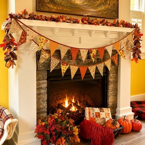 May include: A fabric bunting banner featuring triangular flags in various autumn-themed patterns of orange, brown, and yellow, draped across a white fireplace mantel. The banner is accented with a garland of fabric strips in fall colors.