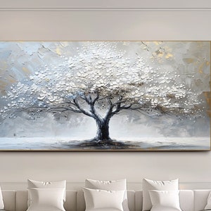 Op de afbeelding: Een groot, abstract schilderij van een witte boom met een grijze achtergrond. Het schilderij hangt aan een witte muur in een moderne woonkamer met een witte hoekbank en een zwarte marmeren salontafel.