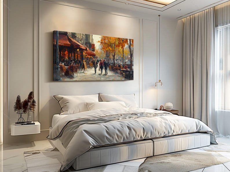 May include: A painting of a Parisian street scene with a cafe on the corner. The painting is in a bedroom setting with a white bed and white curtains.