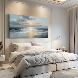 Op de afbeelding: Een slaapkamer met een groot bed, wit beddengoed en een grijze sprei. Boven het bed hangt een landschapsschilderij van een zeegezicht met een zonsondergang. De kamer heeft witte muren, een wit tapijt en lichtgekleurde gordijnen.