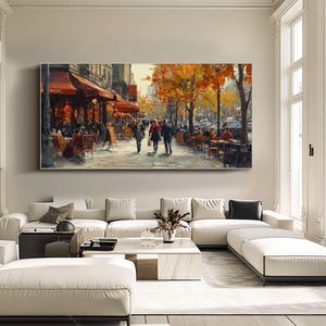 May include: A painting of a Parisian street scene with people walking and sitting at outdoor cafes. The buildings are painted in warm tones, and the trees are in autumn colors. The painting is framed and hanging on a wall.