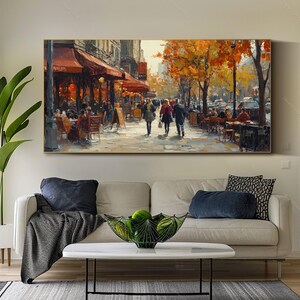 May include: A painting of a Parisian street scene with people walking and sitting at outdoor cafes. The painting features a cafe with a red awning and the word "Boulangerie" on the sign. The trees in the background are painted in shades of yellow and orange.
