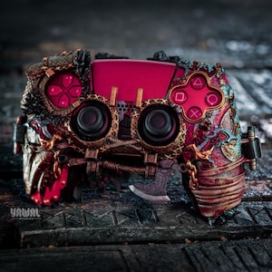 May include: Customized video game controller with a unique, steampunk-inspired design. The controller features a vibrant pink center panel, intricate metallic detailing, and ornate button designs. The overall aesthetic is a blend of futuristic and vintage elements.