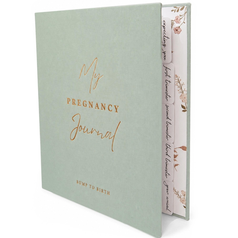 May include: A sage green pregnancy journal with gold foil text that reads My Pregnancy Journal and Bump to Birth. The book features side tabs labelled Expecting you, first trimester, second trimester, third trimester, and your arrival, with floral patterns.