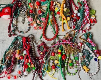 May include: A selection of decorative keychains with a variety of charms and beads. The keychains feature red, green, white, and gold accents, with some including Christmas-themed ornaments. Each keychain is attached to a silver-coloured clasp.