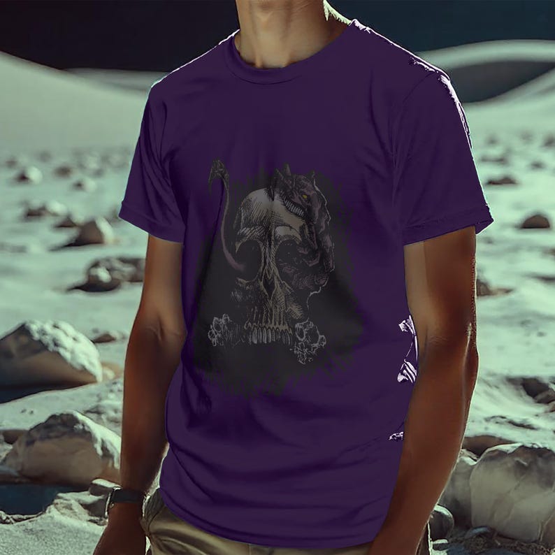 Puede incluir: Una camiseta morada con un gr&aacute;fico detallado en negro y gris de una calavera y un dise&ntilde;o de criatura. La camiseta de manga corta est&aacute; hecha de un material suave. El dise&ntilde;o est&aacute; centrado en la parte delantera de la camiseta.