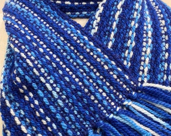 May include: A blue and white striped scarf with fringe. The scarf is made of a soft, textured yarn.