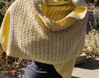 May include: A yellow and purple woven scarf with a geometric pattern. The scarf is draped over a black mannequin.