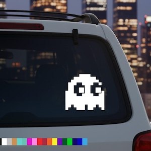Könnte beinhalten: Weißer pixeliger Geisteraufkleber auf einer Autoscheibe. Der Geist hat ein klassisches Videospiel-Design mit quadratischen Augen und einem breiten Mund. Am unteren Rand wird eine Farbpalette mit verschiedenen Farben angezeigt.