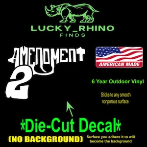 May include: Black die-cut decal featuring the text "AMENDMENT 2" in white, a green rhino logo, and an American flag graphic. The decal is made of 6-year outdoor vinyl and adheres to smooth, nonporous surfaces.