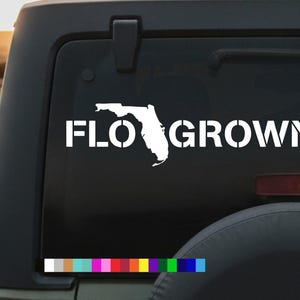 May include: White vinyl decal featuring the outline of Florida with the text "FLO GROWN" in a bold, stencil-style font. The decal is displayed on a black vehicle window, with a color palette at the bottom.