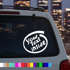 May include: White car window decal with the text "Your Text Inside" in a white oval design. The decal is on the rear window of a white car, with a city skyline in the background.
