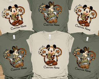 May include: Five t-shirts in different colors with a graphic of Mickey Mouse dressed as an explorer with the text "Let's Get Wild" on each shirt. The shirts are available in green, beige, and white.