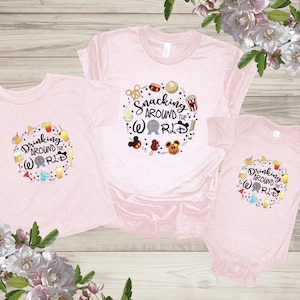 May include: Three pink t-shirts with a Disney theme. The largest shirt says "Snacking Around the World" with a Mickey Mouse head and other Disney icons. The two smaller shirts say "Drinking Around the World" with a Mickey Mouse head and other Disney icons.