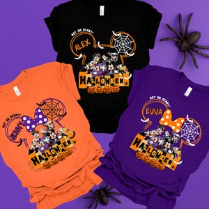 May include: Three orange, purple, and black t-shirts with a Mickey Mouse head design. The shirts feature a group of Disney characters dressed in Halloween costumes. The text on the shirts reads "Not So Scary!" followed by a name, and "Halloween".