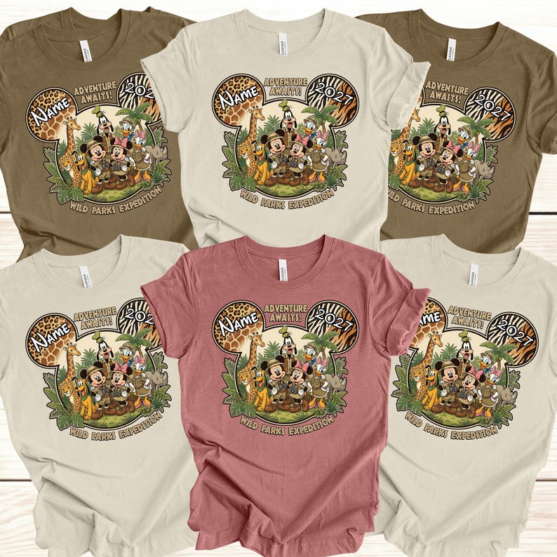May include: A collection of t-shirts in various colors, including tan, brown, and rose. Each shirt features a graphic of Mickey Mouse and friends in safari attire, with the text "Adventure Awaits! 2027" and "Wild Parks Expedition."