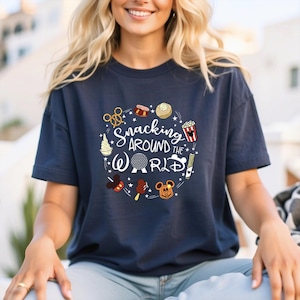 May include: A navy blue t-shirt with a white graphic of a circle with various Disney-themed snacks and the text "Snacking Around the World".