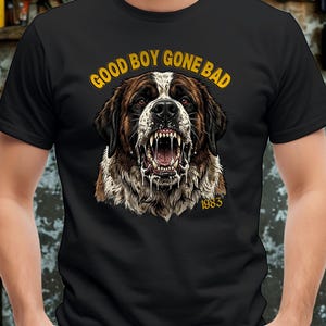 May include: A black short-sleeved t-shirt featuring a graphic of a snarling Saint Bernard dog with drool. The text "GOOD BOY GONE BAD" is printed in yellow above the dog, and the number "1983" is printed in yellow below the dog's chin.