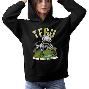 May include: Black hoodie with a graphic of a Tegu lizard. The text "TEGU" is above the lizard, and "Lizard Mode: ACTIVATED" is below. The lizard is black and white, set against a green and blue backdrop.