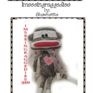 May include: A gray sock monkey with a red mouth and white eyes. The monkey is wearing a white headband and a red heart that says "Be Mine". The monkey is 10 inches tall. The image also includes the text "Imseeingraggedies by: Shawnette 2009".