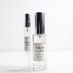 May include: Two clear glass perfume bottles with silver caps. The bottles are labeled "Salon No.001 Eau De Parfum" and "Vella Luxe". The larger bottle contains 30ML/1.04 fl oz of perfume. The smaller bottle is a sample size.