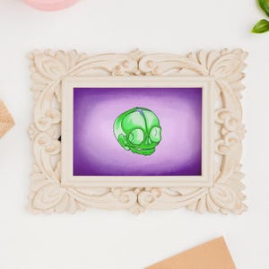 May include: A framed artwork featuring a green skull illustration against a purple background. The skull has detailed features and is set within a decorative, off-white frame. The artwork is a unique piece of wall decor.