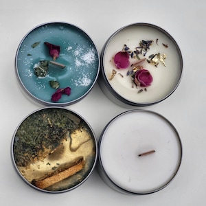 May include: Four tealight candles in metal containers. The candles are topped with various dried flowers, herbs, and gold flakes.