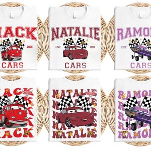 Puede incluir: Camisetas blancas con varios dise&ntilde;os que presentan las palabras "MACK", "NATALIE" y "RAMONE" en negrita. Cada camiseta incluye un gr&aacute;fico de coche de dibujos animados, banderas a cuadros y la palabra "CARS". Las camisetas se muestran sobre un fondo tejido.