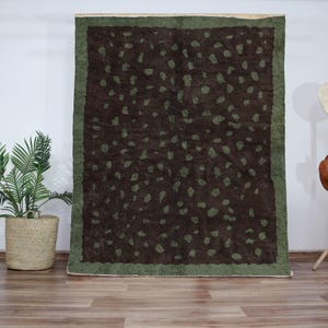 Peut inclure: Un tapis à motifs marrons et verts avec une bordure vert foncé. Le tapis a un motif tacheté.