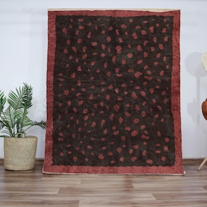 Peut inclure: Un tapis à motifs brun et rouge avec un fond brun foncé et une bordure rouge. Le tapis a un design unique avec une variété de formes et de tailles.