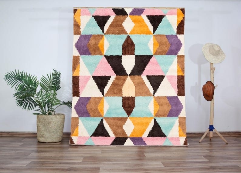 Handmade colorful wool rug featuring a bold geometric pattern with pastel pinks, blues, yellows, and earth tones. Crafted with high-quality hand-knotted wool, this modern Art Deco-inspired rug brings vibrant energy and artistic flair to living rooms, bedrooms, or creative interiors. Plush, durable, and visually striking, it creates a cozy yet dynamic atmosphere in any contemporary or eclectic space.