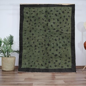Peut inclure: Un tapis vert avec une bordure noire et un motif léopard.