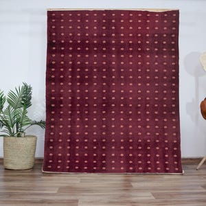 May include: A burgundy rug with a white polka dot pattern. The rug is on a wooden floor.