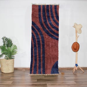 Peut inclure: Un tapis à motifs abstraits bleus et rouges avec un design moderne. Le tapis est en laine et a un poil haut.