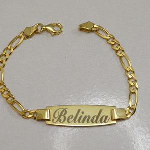 Puede incluir: Un brazalete de cadena de oro con una placa rectangular grabada con el nombre "Belinda".